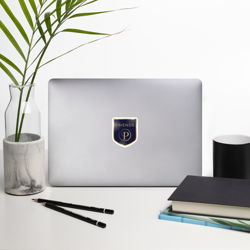 Laptop with a logo on a desk with a plant, pencils, and books.