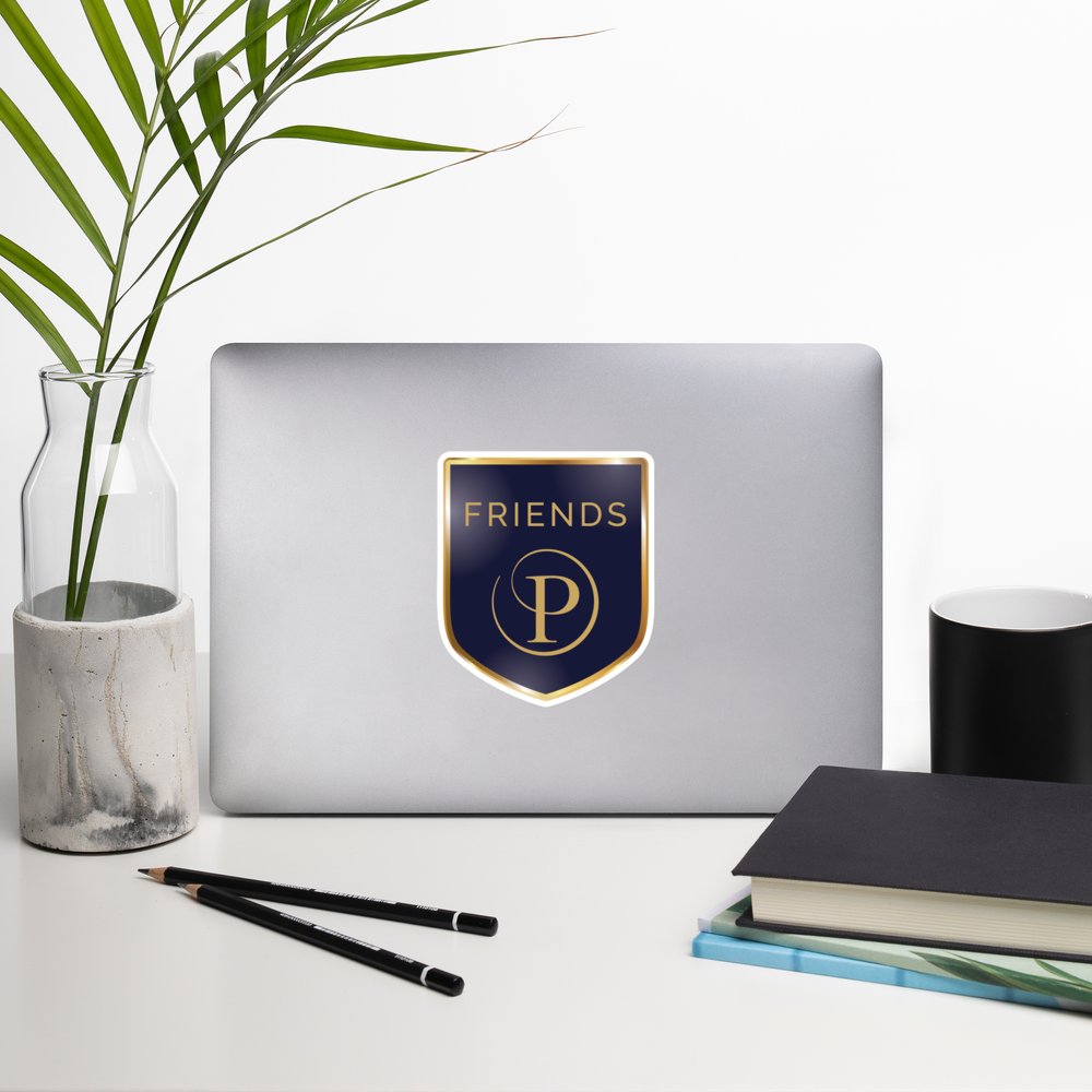 Laptop with 'Friends' logo sticker on a desk with a plant, notebook, and pencils.