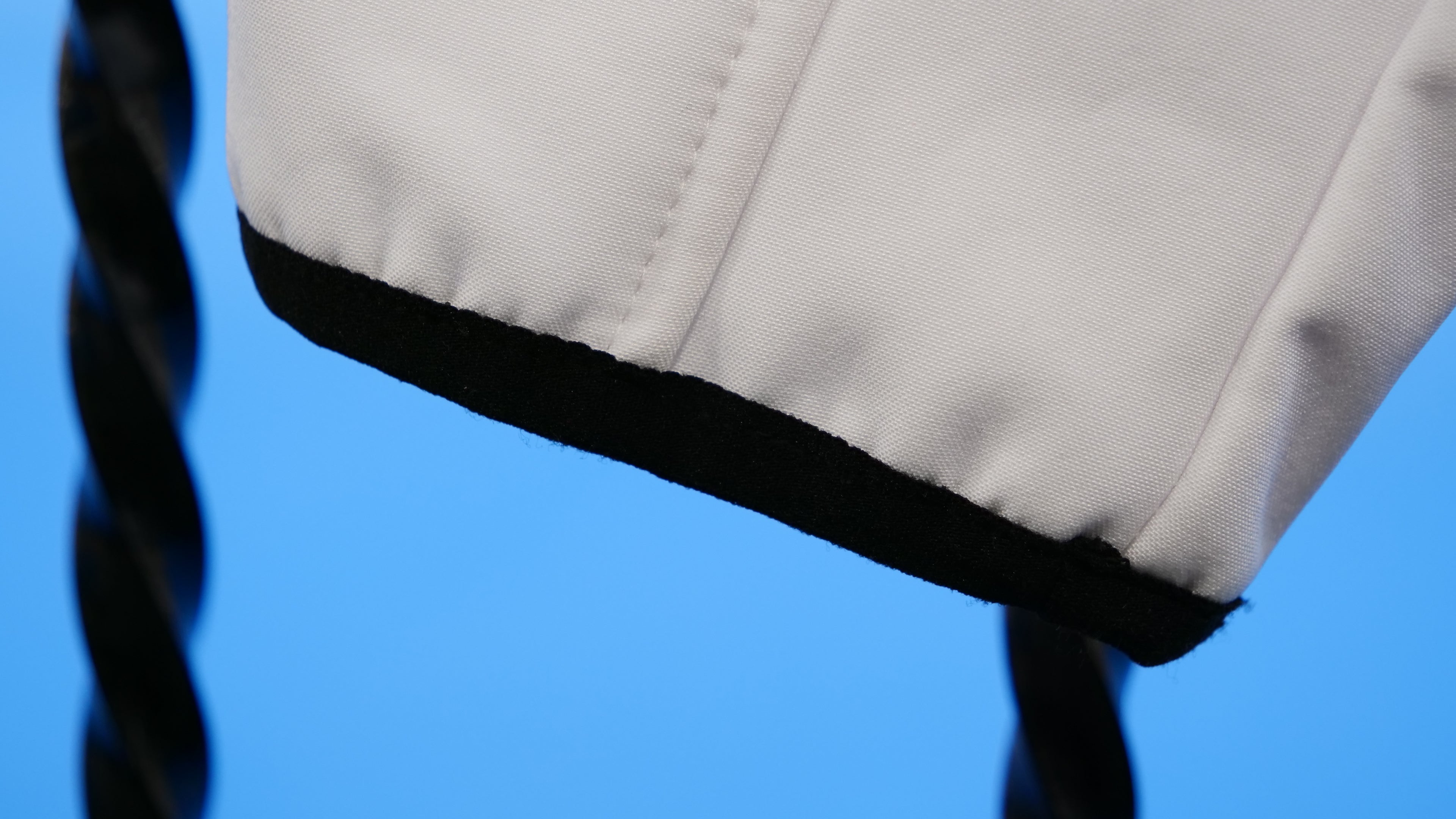 Close-up of a beige fabric with black trim on a blue background